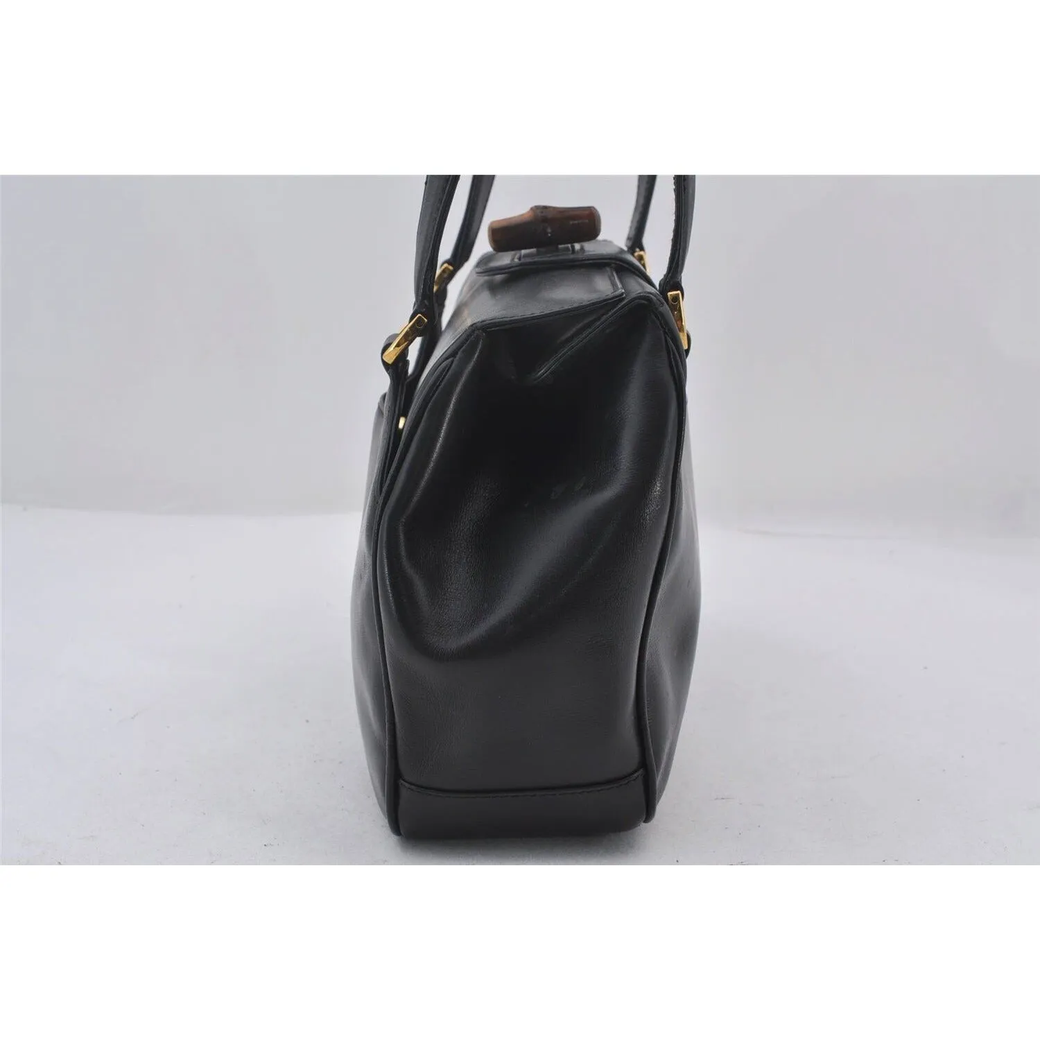 Mod Gucci, black leather shoulder bag with two longer straps, two exterior pockets, a hinged opening, and a gold and bamboo accent clasp