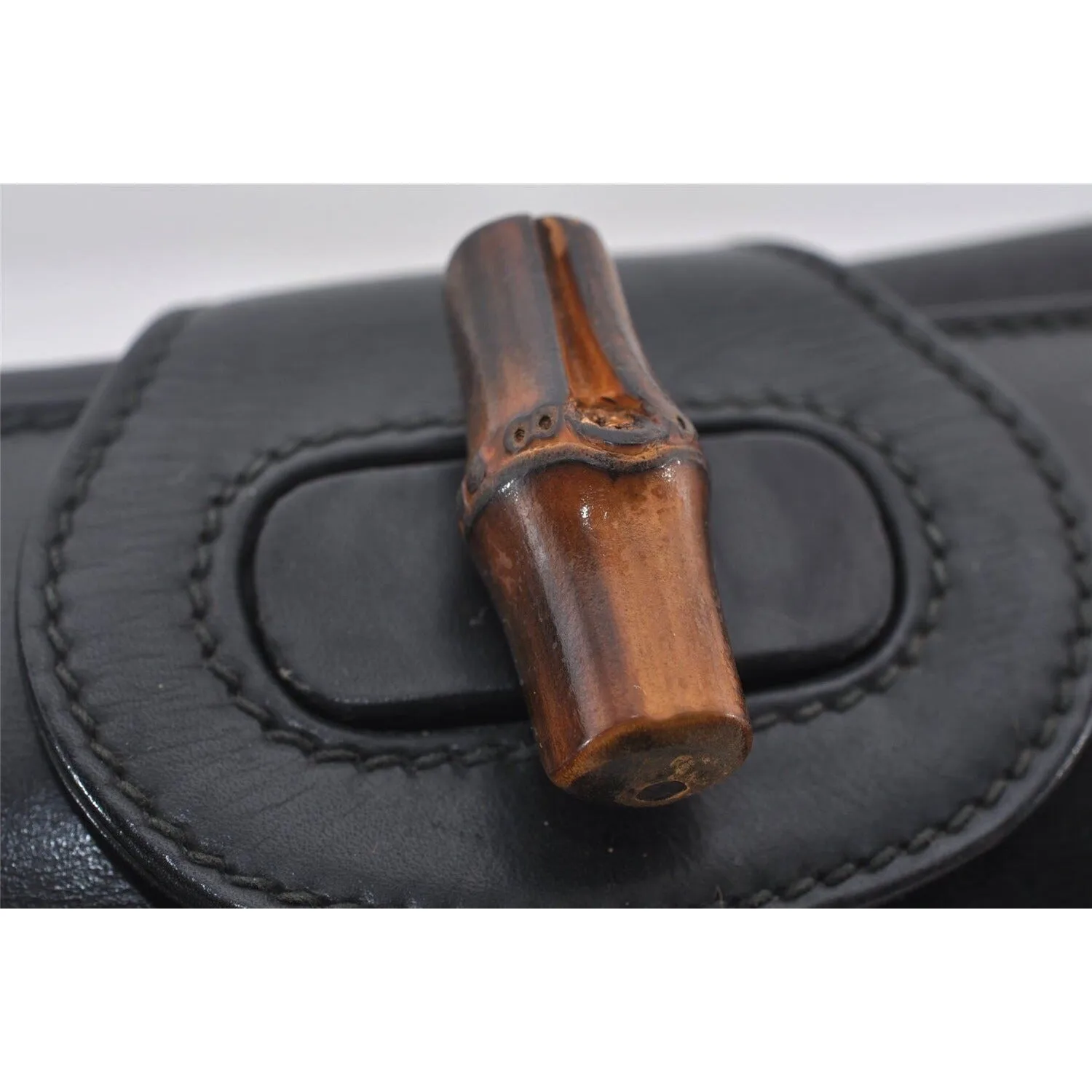 Mod Gucci, black leather shoulder bag with two longer straps, two exterior pockets, a hinged opening, and a gold and bamboo accent clasp